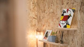 Een houten wand met een lijstwerk en een plank waarop een plant en een klein vaasje staan.