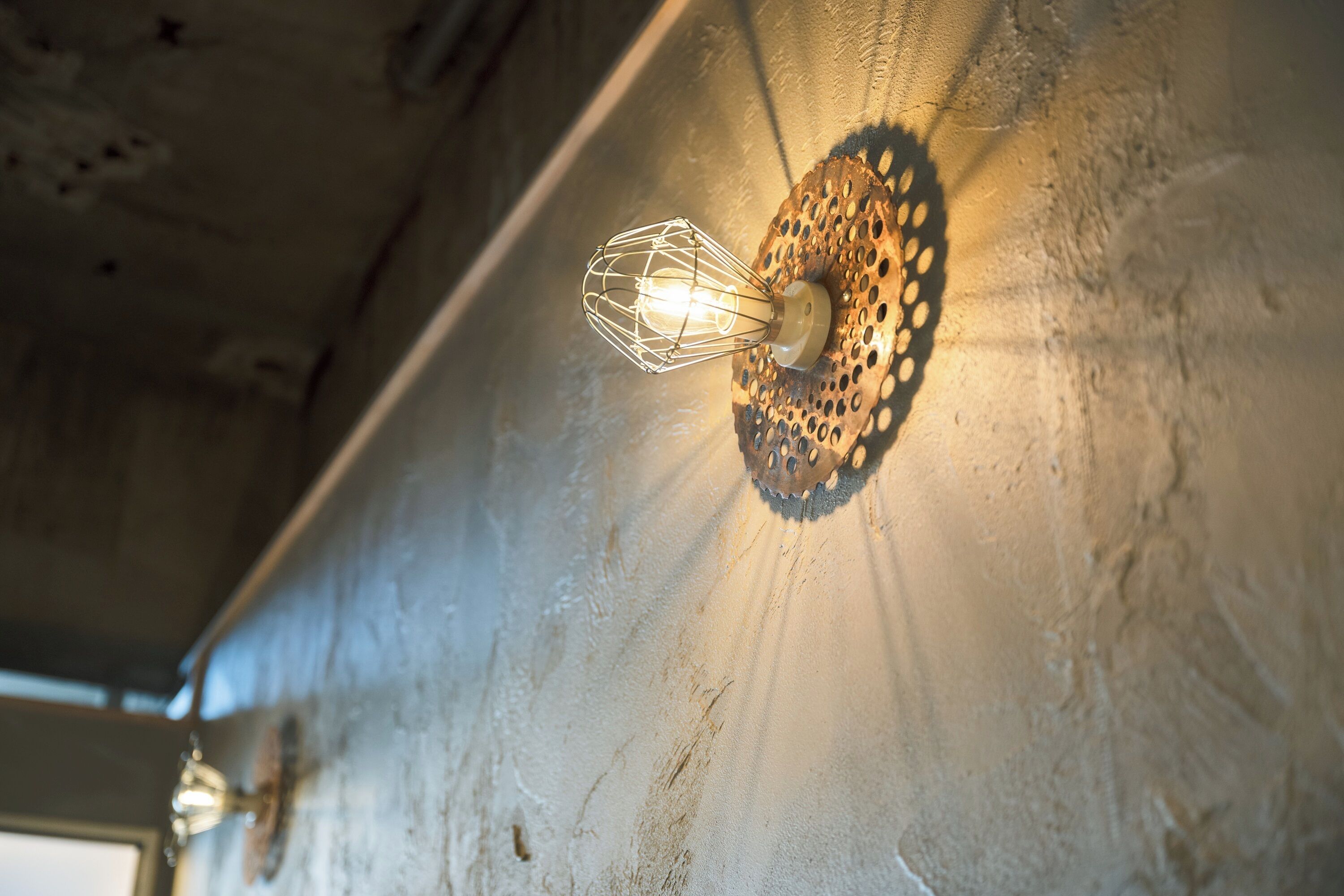 A wall-mounted light fixture with a decorative metal shade.