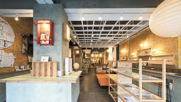 A bookstore with wooden shelves, a reception desk, and a map on the wall. - Kotori Coworking and Hostel Kotohira (Kotohira)