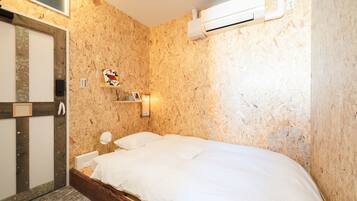 Un dormitorio con pared de madera, una cama, una mesita de noche, un espejo y un aire acondicionado instalado en la pared.