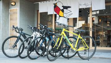 A row of bicycles parked outside a building with a bird mural on the wall.