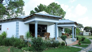 A two-story house with a covered porch, a stone pathway, and a well-maintained garden. - Biko's Villa (Magaliesberg)