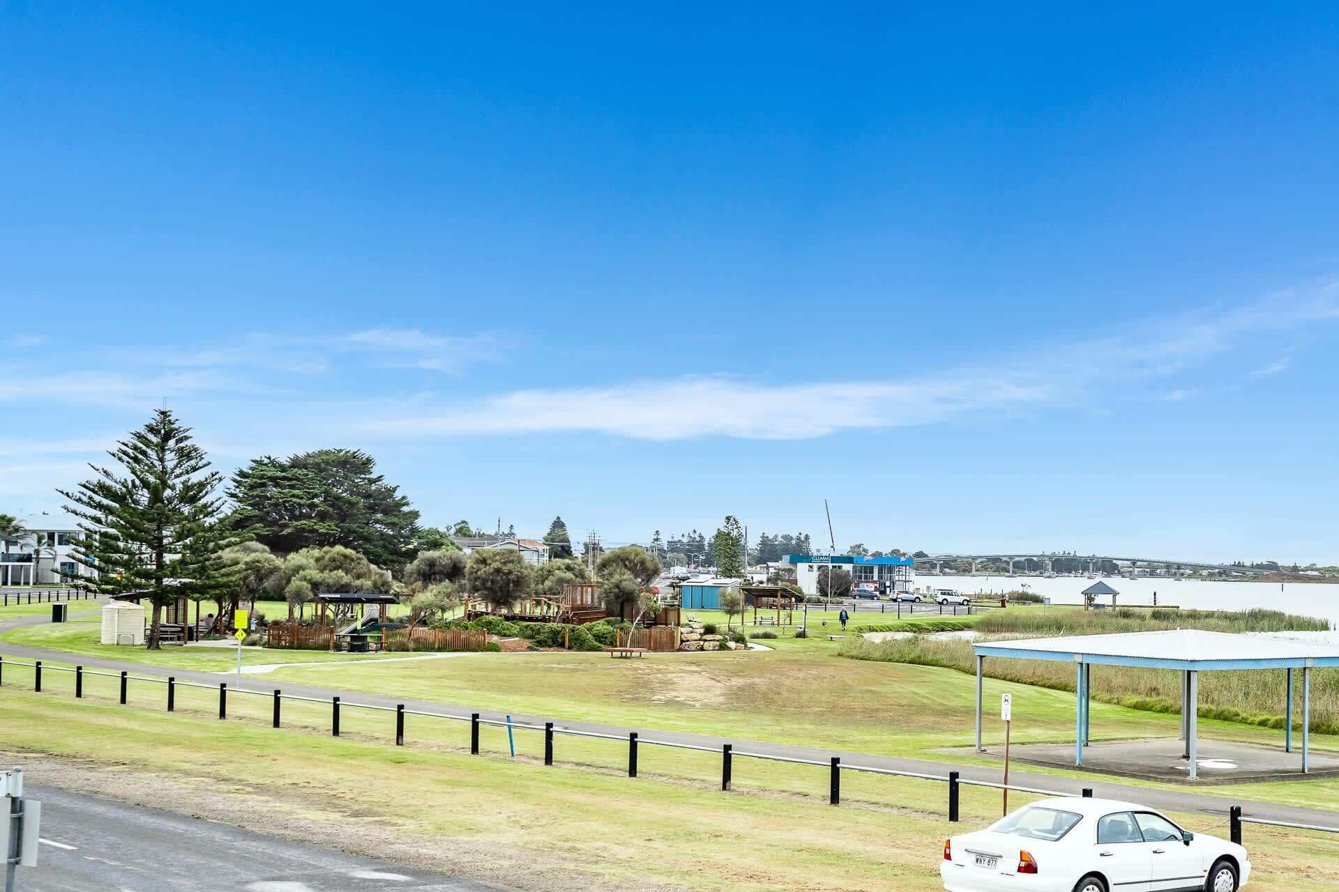 A coastal view with a parking area, a covered pavilion, and a white car.