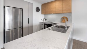 Une cuisine moderne équipée d’un réfrigérateur en acier inoxydable, d’un évier et de meubles de rangement en bois.
