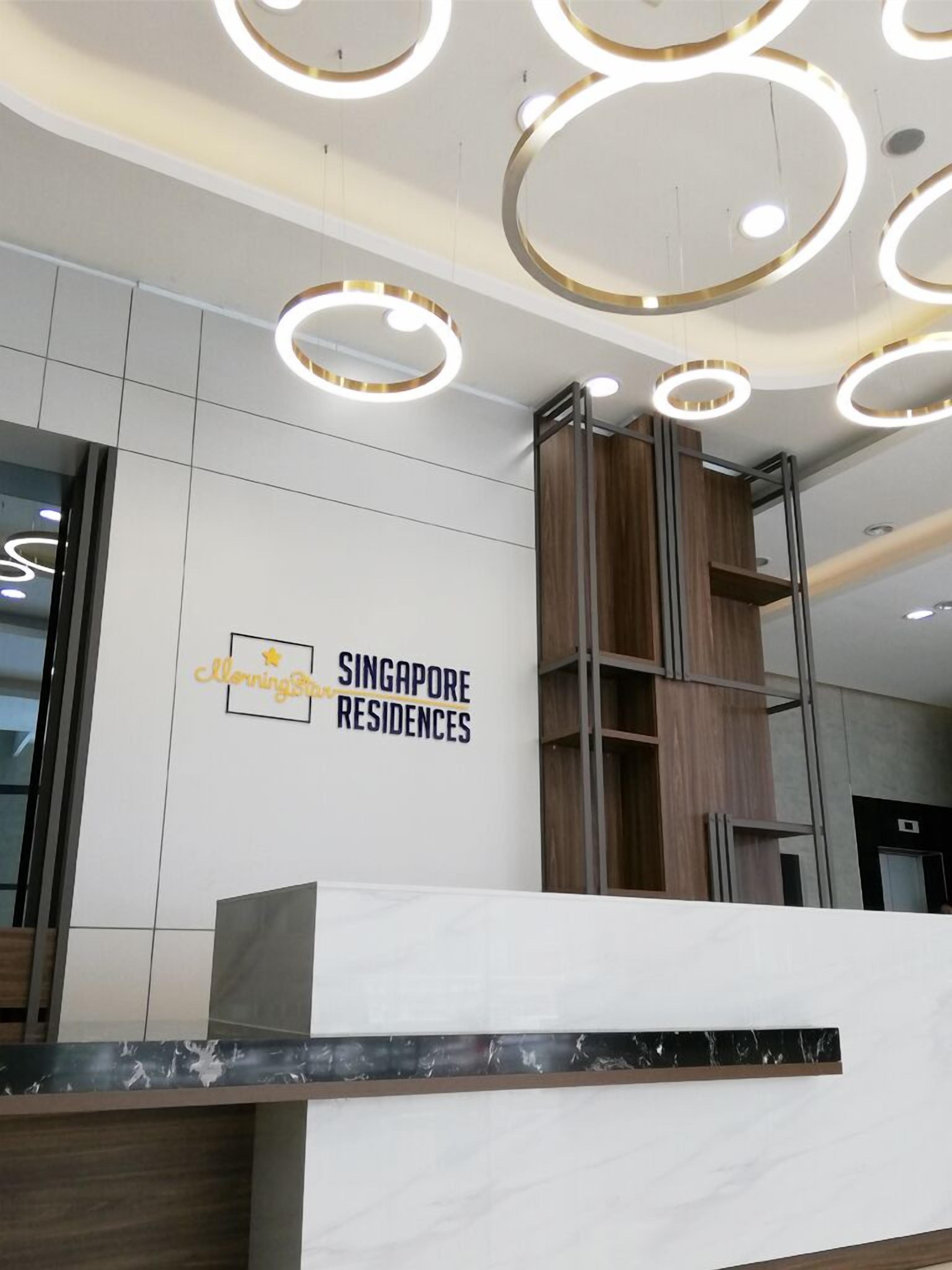 A reception area with a sign for 'Singapore Residences' and modern circular lighting fixtures.