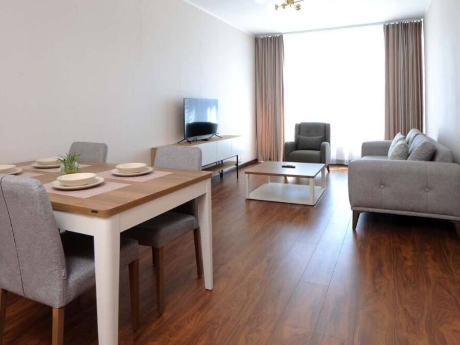 Uma sala de estar moderna com área de jantar, sofá e televisão.