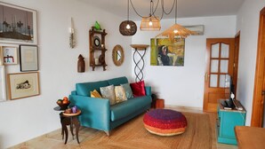 Un salón con un sofá color turquesa, un tapete redondo y varias decoraciones en la pared, incluyendo cuadros enmarcados y un reloj.