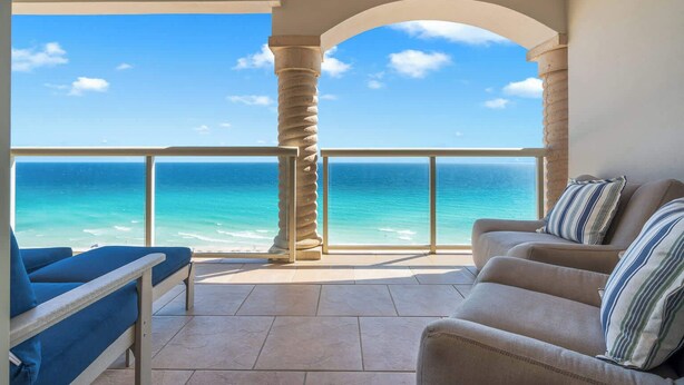 A balcony with a view of the ocean, a sofa, and a chair. - Beach Club 1105 - 𝑪𝒐𝒂𝒔𝒕𝒂𝒍 𝑹𝒆𝒕𝒓𝒆𝒂𝒕 (Pensacola Beach)