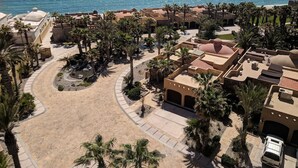 Vista aérea de un resort con playa, palmeras y una vista despejada del océano.