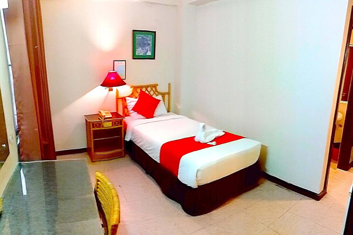 A hotel room with a bed, a nightstand, a desk, and a chair.