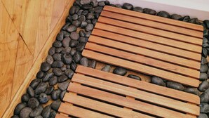 Un terraço de fusta amb llistons, envoltat d'un llit de pedres llises.
