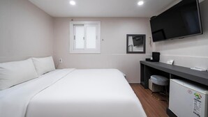 Una camera d'albergo con un letto, una scrivania con una sedia, una televisione e un frigorifero.