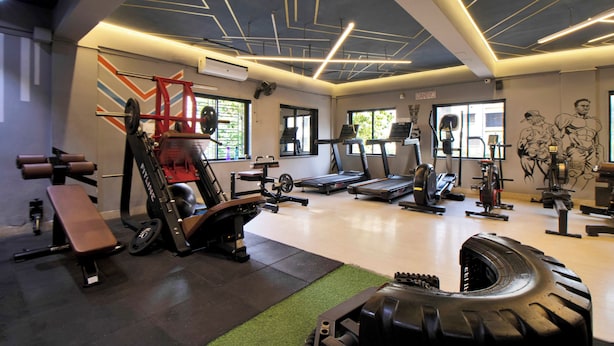 A gym with various exercise equipment, including treadmills, weight machines, and a bench. - iROOMZ Growval Residency (Barasat)