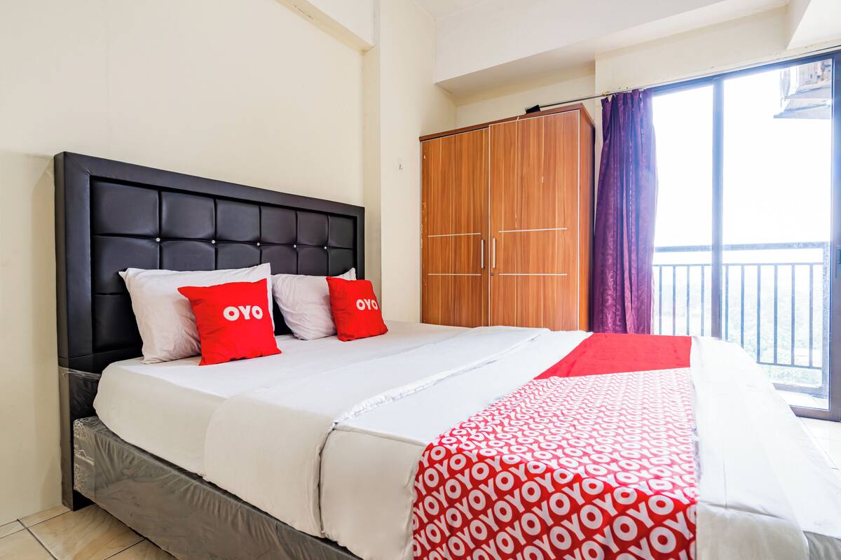 Una habitación de hotel con una cama grande, un armario y un balcón con cortinas.