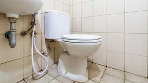 Een badkamer met toilet, wastafel en betegelde wanden.