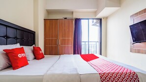 Een hotelkamer met een bed, een kledingkast, een televisie en een balkon met gordijnen.