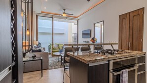 A modern kitchen with a central island, built-in oven, and a dining area with a sofa and chairs. - Penthouse in Romantic Zone! Pacifica 604 2BD Penthouse for rent in Old Town, Pue (Puerto Vallarta)