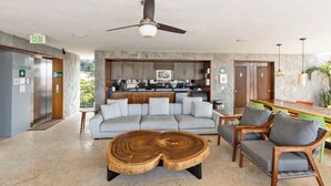 A modern lobby with a sofa, wooden coffee table, and chairs. An elevator and a sign indicating the exit are visible. - Penthouse in Romantic Zone! Pacifica 604 2BD Penthouse for rent in Old Town, Pue (Puerto Vallarta)