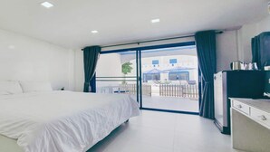 Habitación de hotel con cama, escritorio, televisor y balcón con vista a la calle.