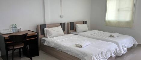 A hotel room with two beds, a desk, and a chair.