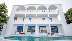 Un edificio de varios pisos con piscina al frente.