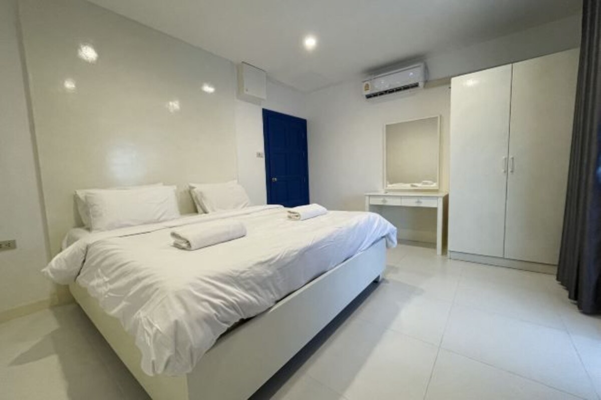 Una habitación de hotel moderna con una cama grande, un escritorio y un armario.