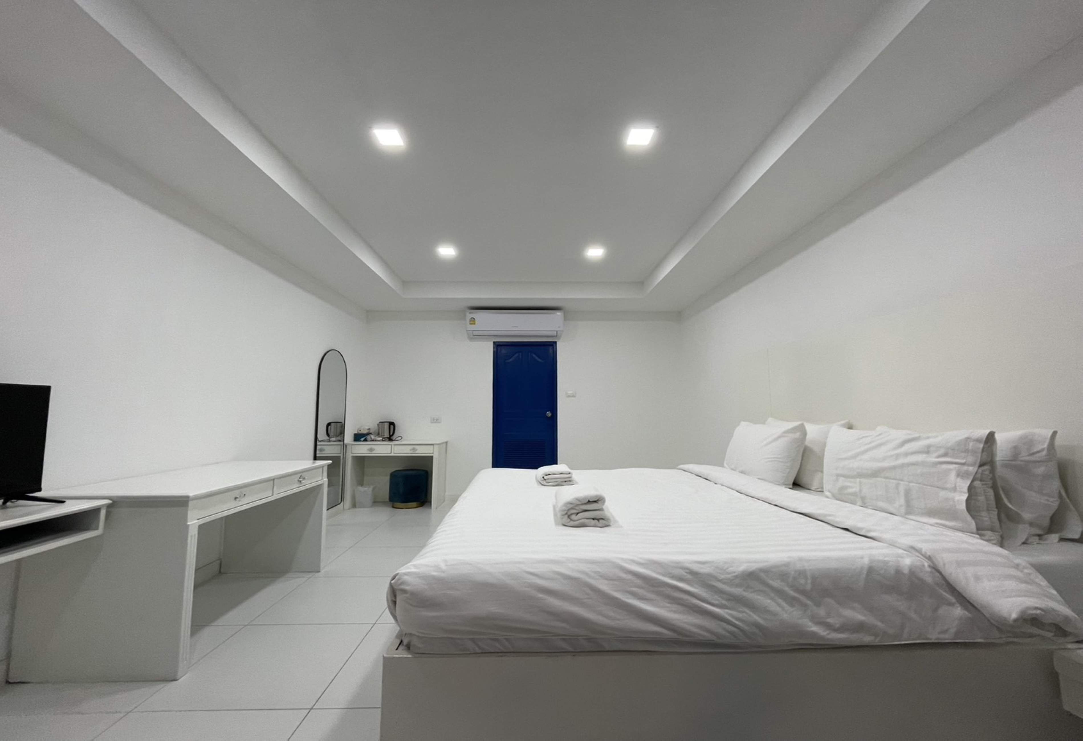 Una habitación de hotel moderna con una cama, un escritorio, una silla, un televisor y una puerta azul.
