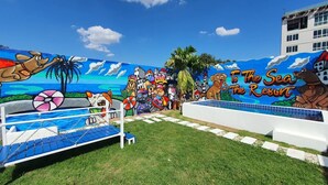 Un mural colorido en The Sea Resort, que muestra una escena de playa con perros de dibujos animados y palmeras.