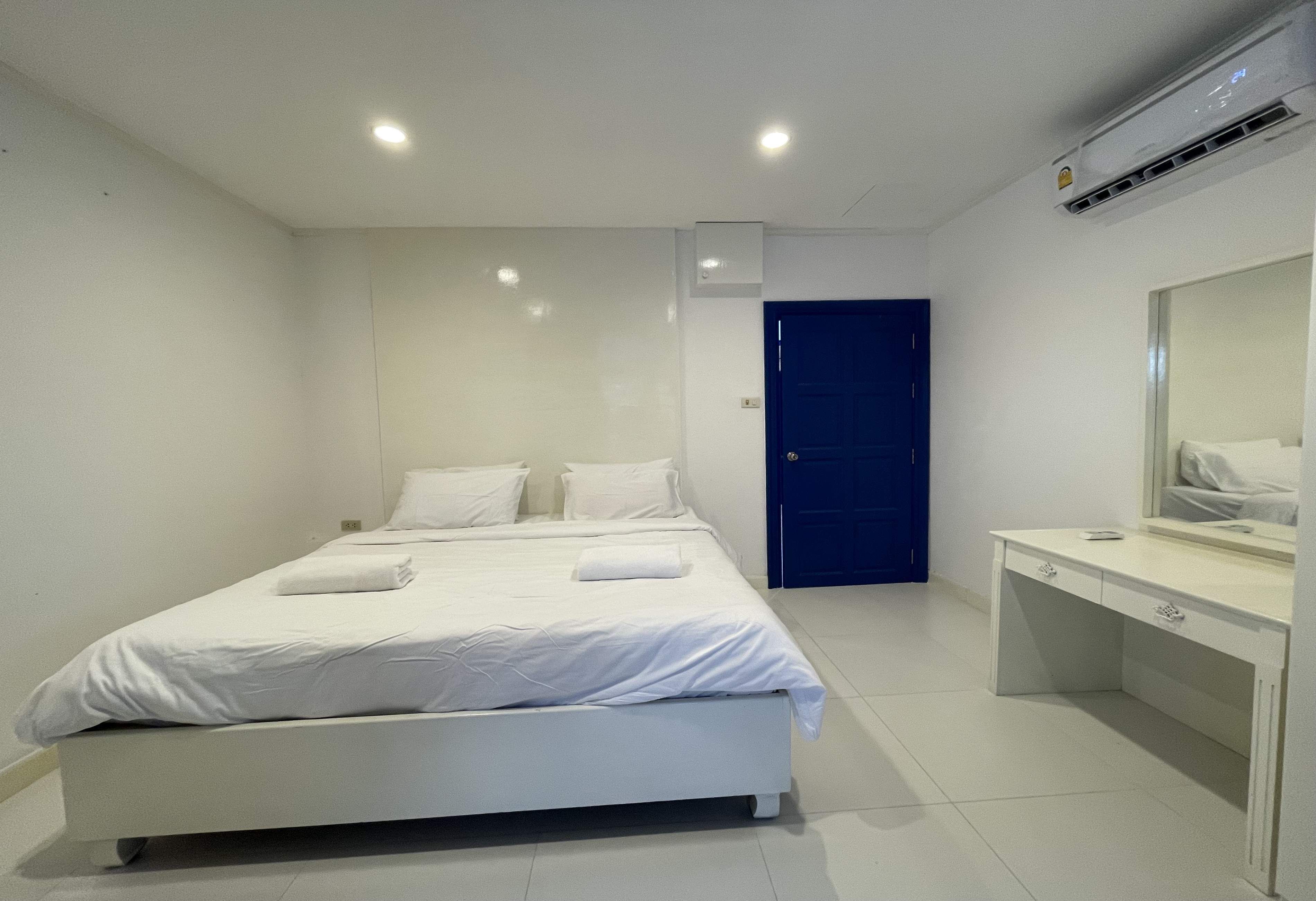 A modern hotel room with a large bed, a desk, and a mirror.