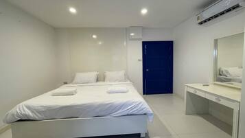 A modern hotel room with a large bed, a desk, and a mirror.