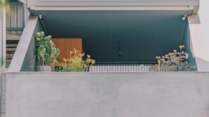 A modern two-story building with a balcony, large windows, and various plants. - J Youai House (Tainan)