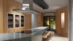 A modern kitchen with a granite countertop, wooden cabinets, and a built-in stove. There are bar stools and a large window with a view of greenery. - J Youai House (Tainan)