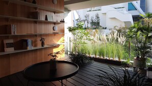 A modern interior with wooden shelves, a round table, and potted plants. - J Youai House (Tainan)