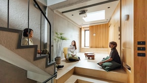 A modern interior with a staircase, a large mirror, a potted plant, and a wooden cabinet. - J Youai House (Tainan)