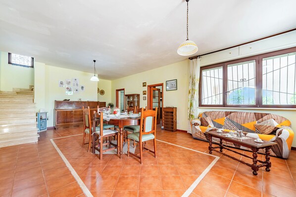 Amplia sala de estar con mesa de comedor, sillas, sofá y una escalera.