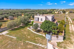 A single-story house with a flat roof, surrounded by a garden and trees, with a clear sky above. - Villa Mattalia 500m From Sea (Manduria)