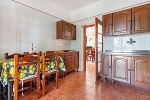 A kitchen with wooden cabinets, a dining table with chairs, and a tiled backsplash. - Villa Mattalia 500m From Sea (Manduria)