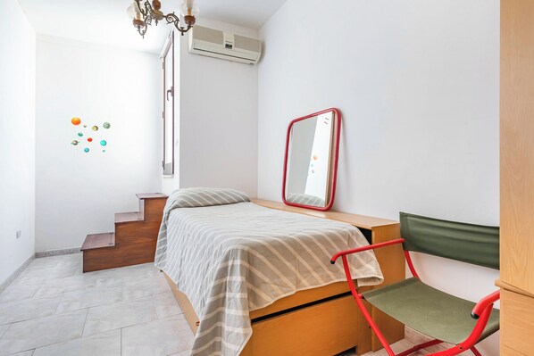 Un dormitorio con cama, una silla, un espejo y una escalera.