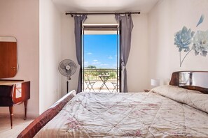 A bedroom with a bed, a fan, a piano, and a view of the outdoors. - Villa Mattalia 500m From Sea (Manduria)