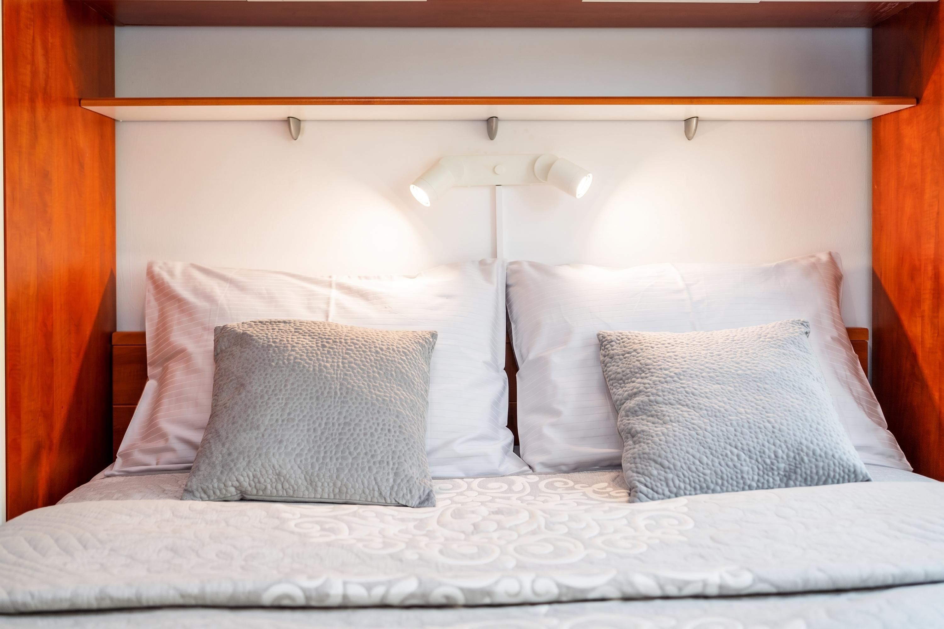 Una cama con una colcha estampada, dos almohadas y una lámpara de noche.