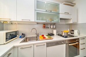 A modern kitchen with a built-in microwave, stainless steel sink, and a stove.