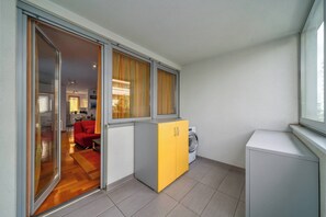 A compact living space with a sliding glass door leading to a dining area, a washing machine, and a small kitchenette.