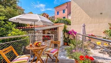 Une terrasse avec une table, des chaises et un grand parasol.