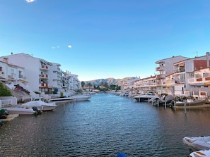 Stunning waterfront views of a tranquil canal lined with boats and surrounded by Mediterranean-style buildings with balconies and terraces.