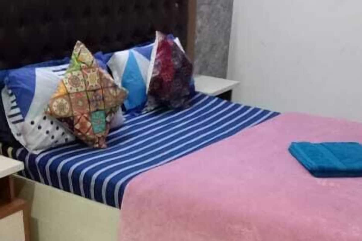 A bedroom with a bed, pillows, a nightstand, and a wall with a painting.
