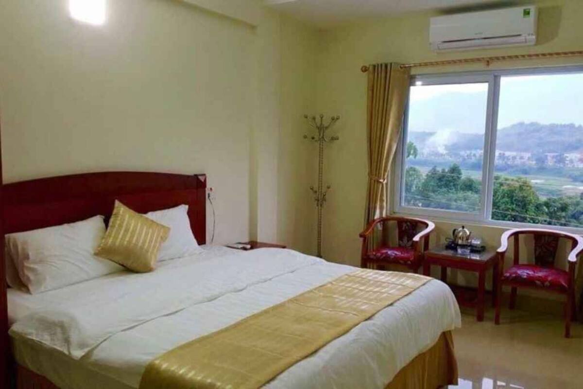 A hotel room with a bed, a window with a view, and a small table with chairs.