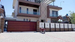 A modern building with a large garage door, a motorcycle parked in front, and a gated entrance. - Panorama Guest House (Islamabad)