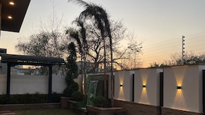 A modern outdoor patio with a concrete floor, a wooden bench, and a small water feature. - Panorama Guest House (Islamabad)