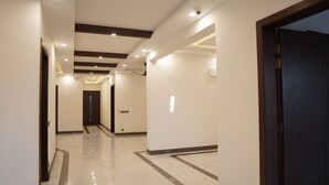 A modern hotel corridor with a polished marble floor, recessed lighting, and a dark wooden door on the right. - Panorama Guest House (Islamabad)
