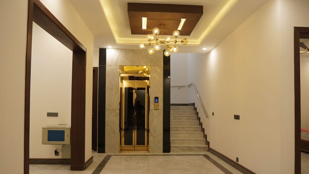 A modern interior with a marble floor, a staircase, and a chandelier. - Panorama Guest House (Islamabad)